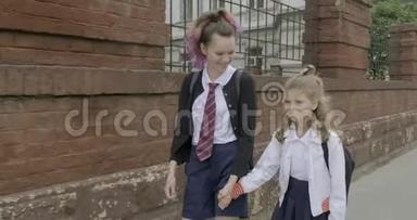 两个女孩姐妹牵着手上学，孩子们穿着<strong>校服</strong>，背着背包